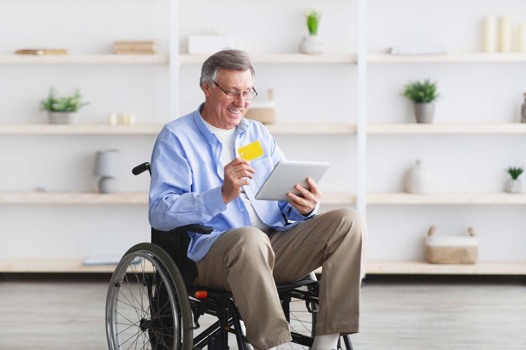 happy-senior-man-in-wheelchair-shopping-online-wit-AHKQ4NS.jpg